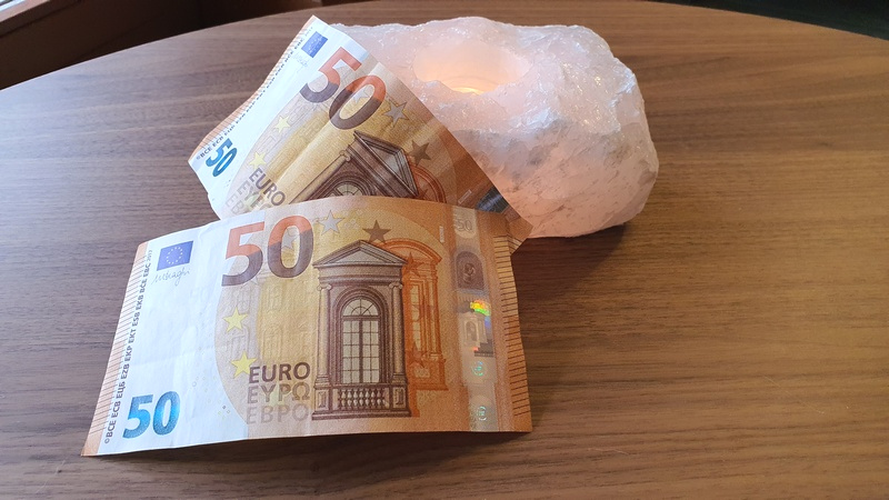 due banconote da 50 euro su tavolo in legno e candela vicina
